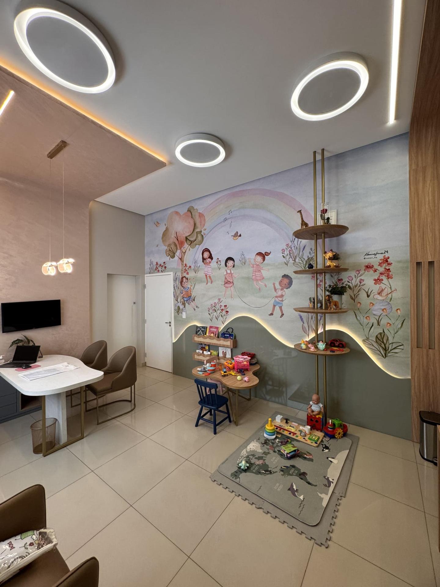 Consultório pediátrico amplo com mural de arco-íris e espaço lúdico